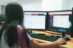 女性在双屏台式电脑上工作。