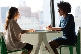 两个女人在一张桌子旁聊天。