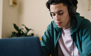 男孩戴着耳机使用笔记本电脑。