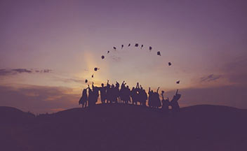 轮廓的人站在一座小山上,毕业帽扔到空气中。