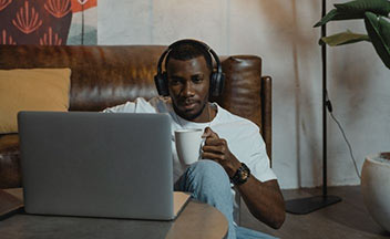 男子戴着耳机使用笔记本电脑。