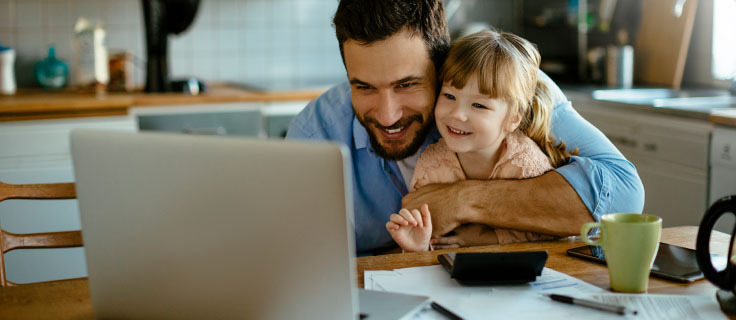 父亲和女儿看着笔记本电脑微笑。